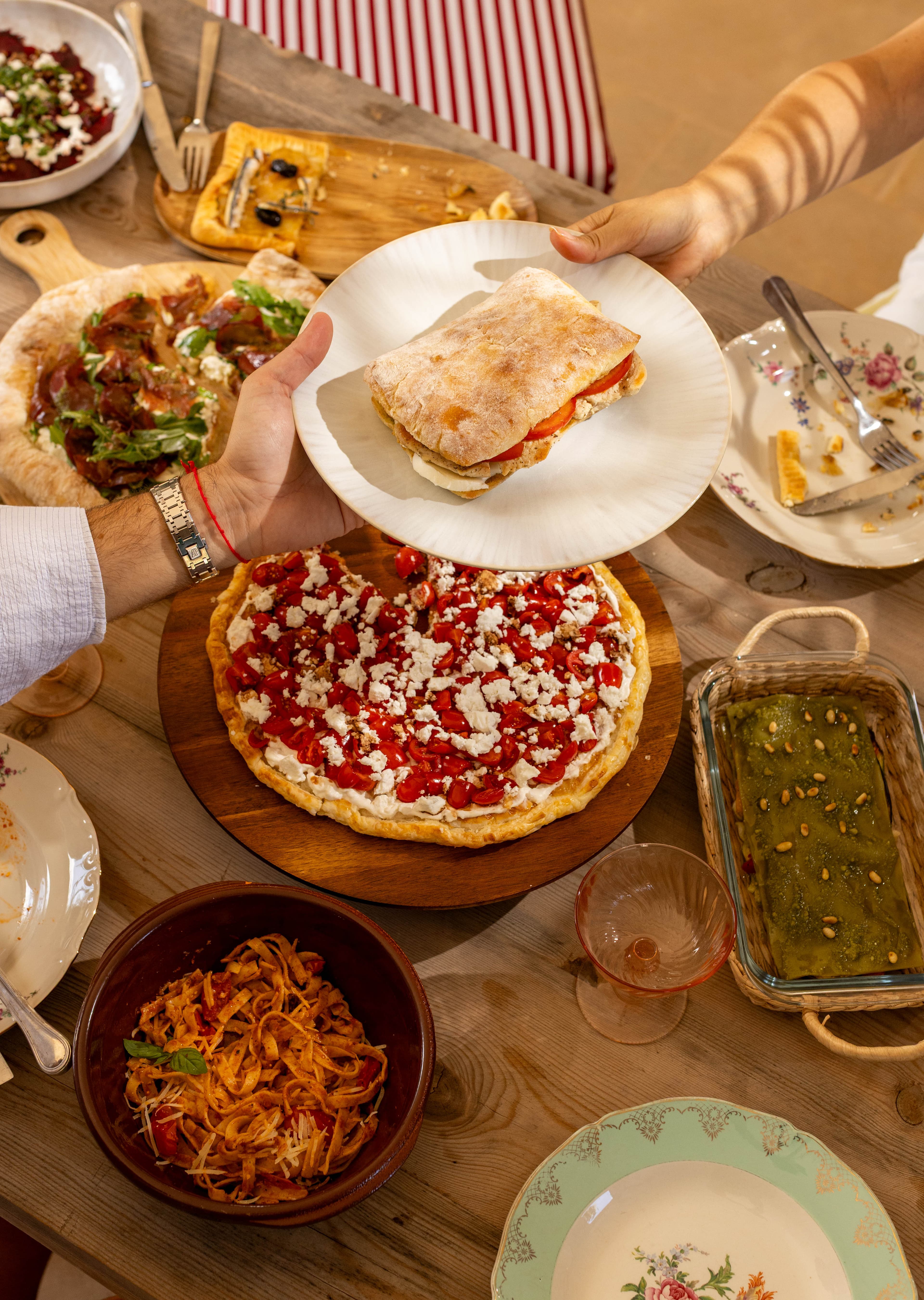 Mains qui se passent les plats au-dessus d'une tablée généreuse